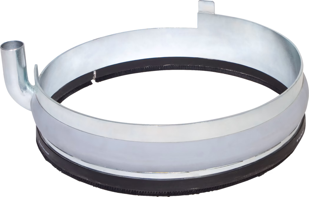 WOLFF_Dummy_72462_74177_Dust ring with extraction outlet_2025-08 En metallisk cirkulær ring med en glat, skinnende overflade og en sort gummistrimmel på bundkanten. Den har et udløbsrør på venstre side og en lille not på højre side, hvilket tyder på, at den er designet til en specifik mekanisk eller industriel funktion, sandsynligvis relateret til at holde eller sikre komponenter sammen.